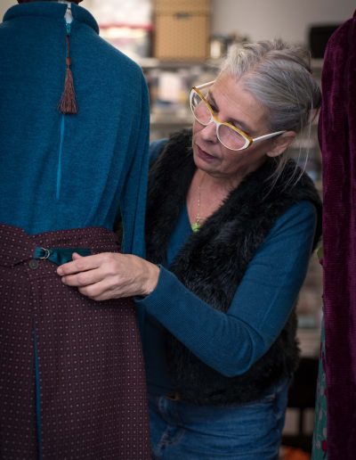 Artisan effectuant la vérification des finitions de la ceinture smockée de la Jupe Kyoto, ornée de perles de verre, en tissu recyclé.