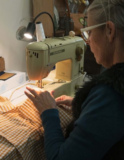 Travail artisanal sur une machine à coudre, confection de vêtements et accessoires à partir de tissus recyclés.