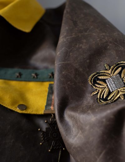 Détails de la Veste Médaillée, confectionnée en tissu recyclé, avec poches à soufflet, pressions et médaille chinée.